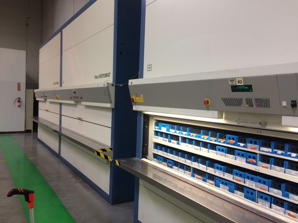 automated vertical storage system with organized parts trays in warehouse